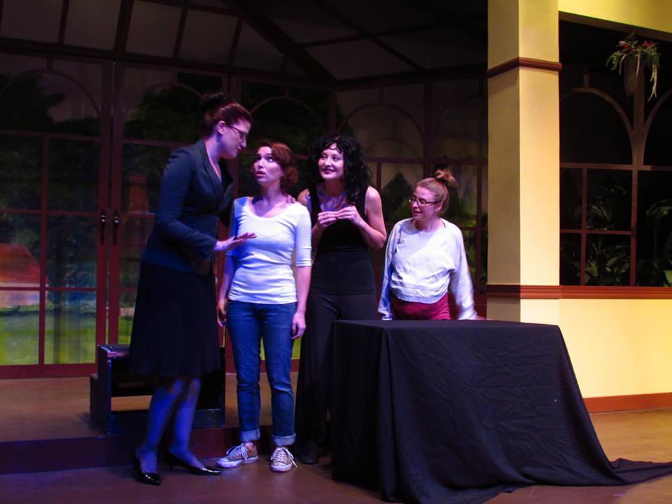 Teacher Mrs. White (Adriana Roze) tells Mandy a demonic way to get back at the mean girls, as fellow coven members Dolores (Rebecca Larsen) and Lorraine (Julia Griswold) look on.