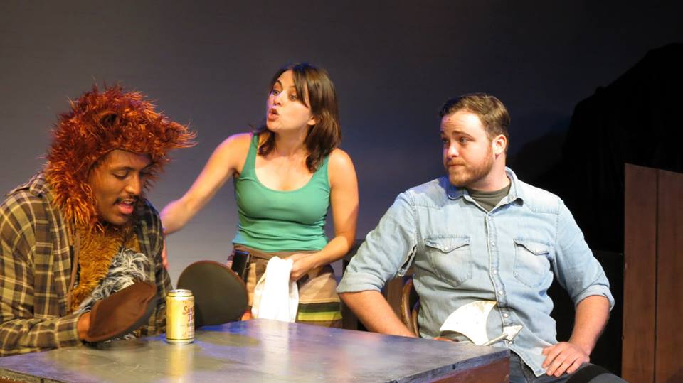 Hank (Brent Davis) can't pick up his drink in his bear hands. Wendy (Heather Schmidt) and Woody (Dylan Lahr) offer their support.