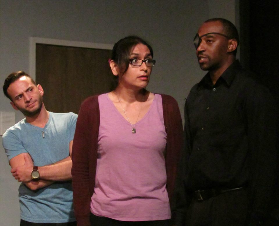 Marian's new co-worker Dave (Matt Valle) looks on skeptically as Nick Furious (Victor Isaac) tries to recruit Marian for some superheroics.