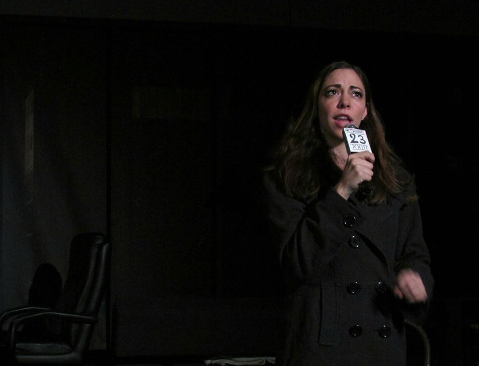 A newscaster (Angela Sauer) reports on the murder of Dr. Krump.